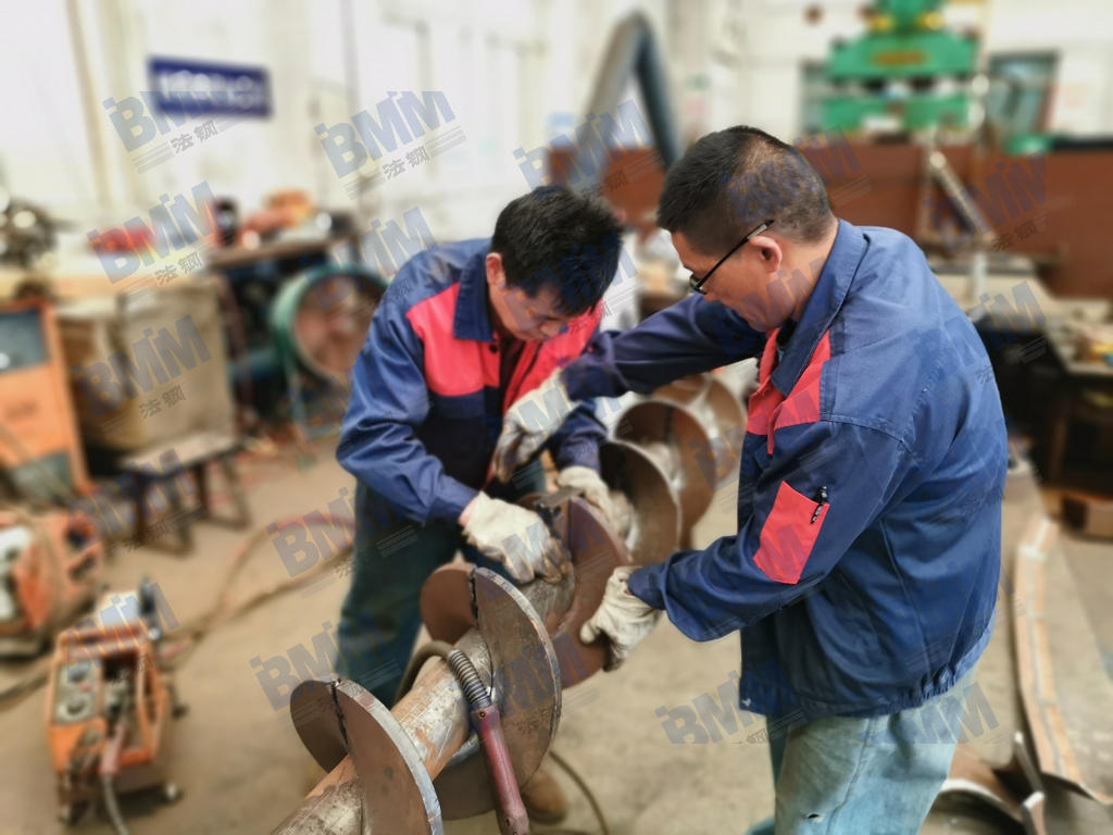 法钢技术人员正在对耐磨螺旋输送部件进行组装和焊接